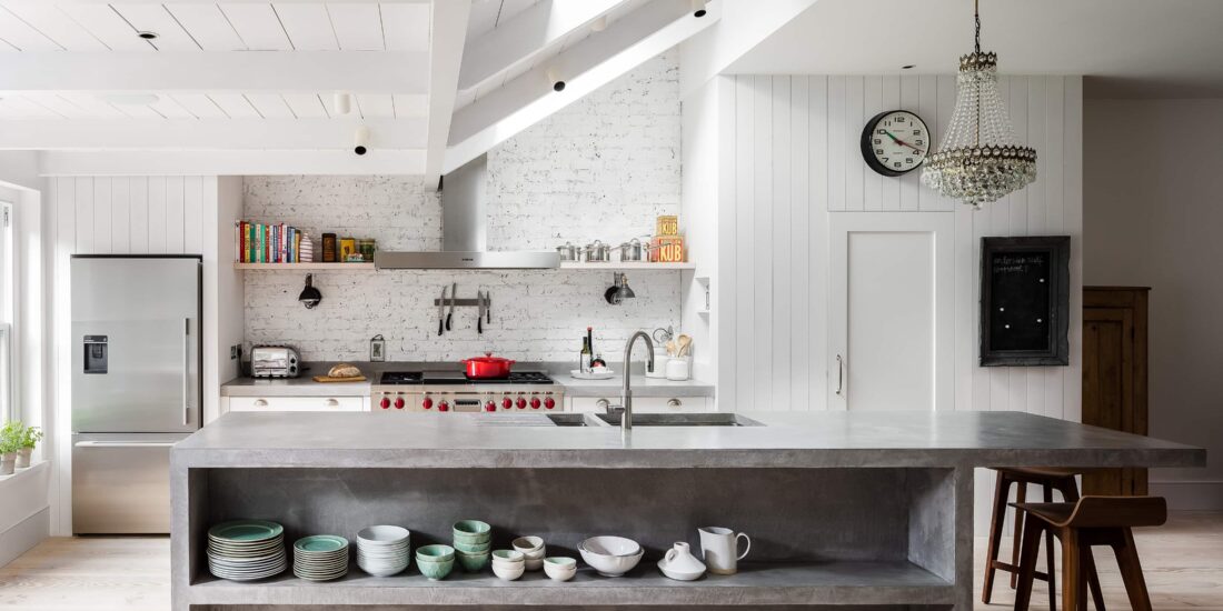 Cement island wit sink, shelves and breakfast bar, paired with classic wood plank and distressed brick walls.